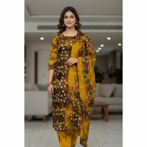 A woman wearing a stylish mustard yellow and dark brown batik print three-piece suit featuring a long kameez, dupatta, and salwar